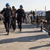 Des Casques ONU français escortent un homme détenu à travers un camp de personnes déplacées en Haïti.