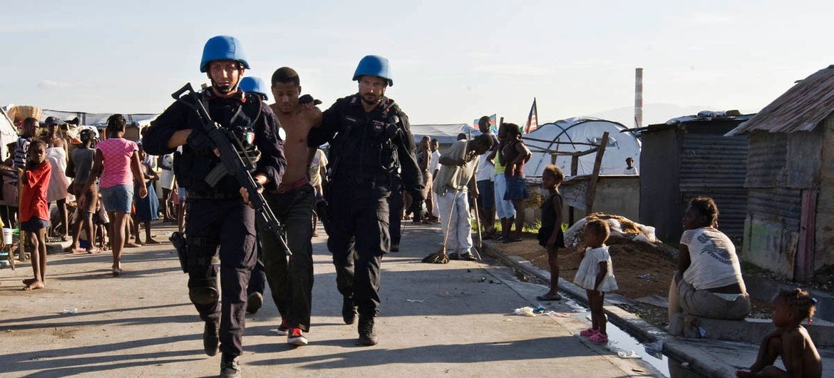 Des Casques bleus français escortent un détenu d'un camp de personnes déplacées en Haïti lors d'une opération de sécurité menée par des militaires et des policiers de l'ONU avec la police nationale haïtienne en juin 2010.