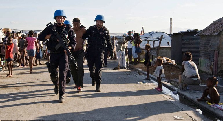 French UN peacekeepers escort a detained man from a camp for internally displaced persons in Haiti during a security operation carried out by UN military and police along with the Haitian National Police in June 2010.