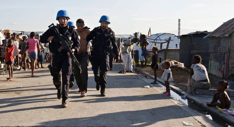 Des Casques bleus français escortent un détenu d'un camp de personnes déplacées en Haïti lors d'une opération de sécurité menée par des militaires et des policiers de l'ONU avec la police nationale haïtienne en juin 2010.