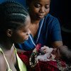 在利比里亚一个人口基金支持的健康中心，21岁的Bendu从助产士手中接过她刚刚出生的女儿。