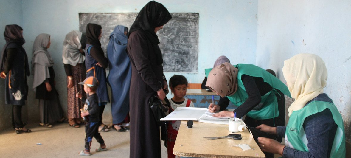 نساء ورجال أفغان يسجلون أسماءهم في سجلات الناخبين في مركز في باميان، قبل الانتخابات المقررة في أكتوبر/تشرين الأول 2018.