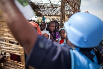 A UNMID police officer speaks with children at a school run inside a camp for internally displaced persons.