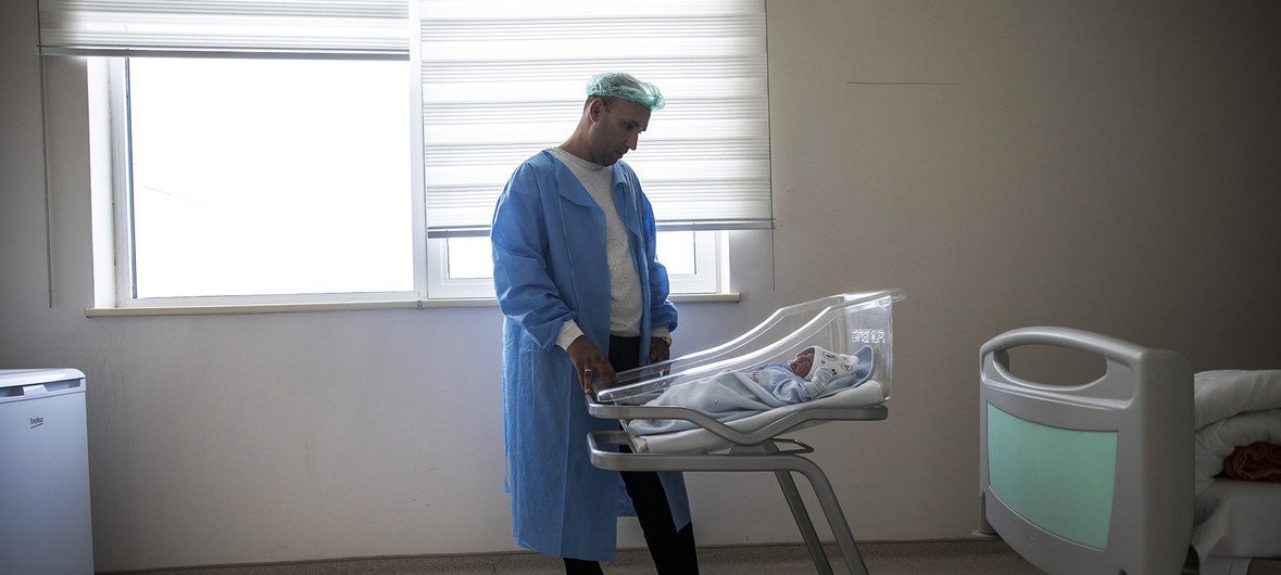 土库曼斯坦的一位父亲站在他刚出生的第二个孩子旁边。