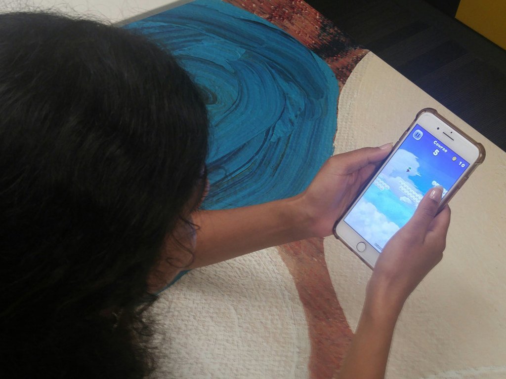 Une jeune femme utilisant son portable. L'OMS a lancé HearWHO, une application gratuite pour appareils mobiles qui permet aux personnes de vérifier régulièrement leur audition