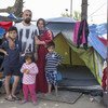 Youssef, a Kurdish-Iraqi from the city of Zakho, stands with his wife and kids outside their small tent in the Diavata reception site near Thessaloniki in northern Greece.
