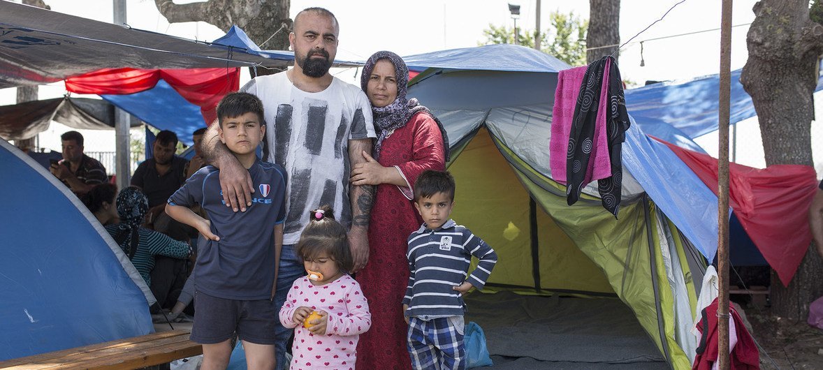 Youssef, a Kurdish-Iraqi from the city of Zakho, stands with his wife and kids outside their small tent in the Diavata reception site near Thessaloniki in northern Greece.