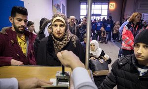 In Germany, a UN resettlement programme gives families hope. Here, an immigration officer stamps the passports of a Syrian family that has just landed at Hanover airport on a charter flight from Egypt.