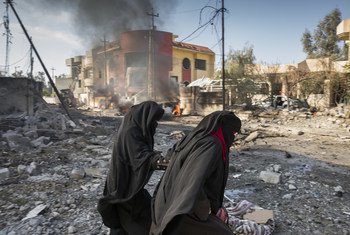  Civilians pass a burning automobile following a suicide car bombing.in Mosul, Iraq, 