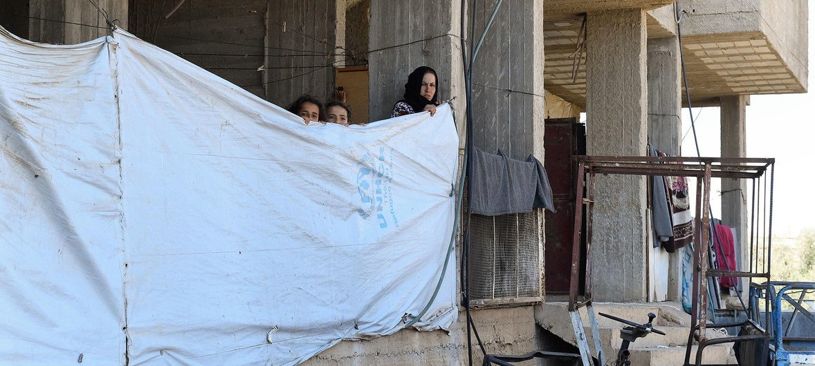 In this file photo, a woman ties a tarpaulin to use as a makeshift wall in an abandoned building in Dara'a, Syria. Recent intensification in fighting has displaced an estimated 330,000 from the region.