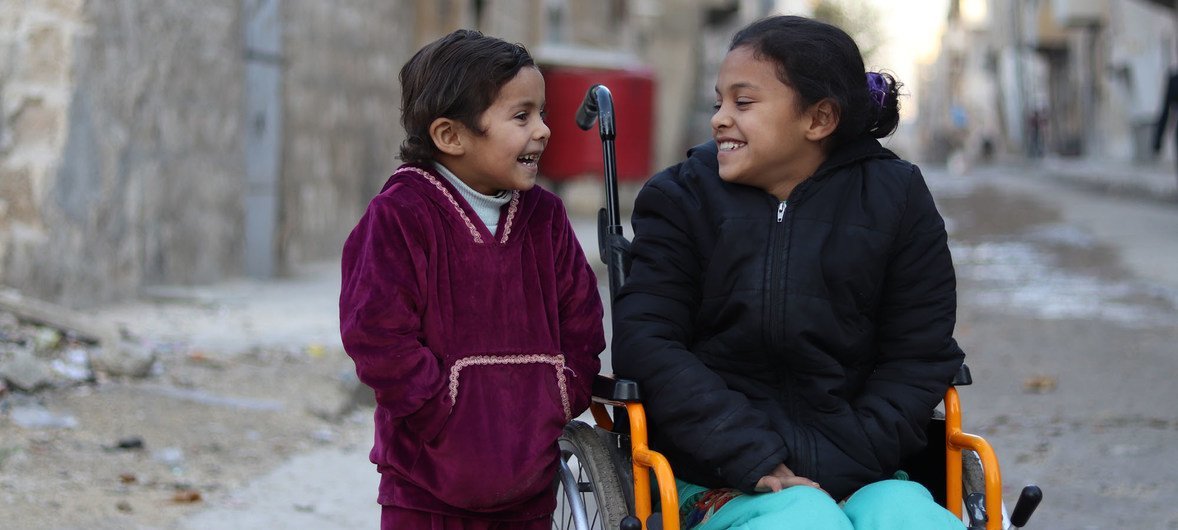 Une fille de 8 ans assise dans un fauteuil roulant à côté de sa sœur de 5 ans, près de leur maison à Alep Est, en Syrie. L’enfant paralysée a perdu l'usage de ses jambes après l’explosion d’une bombe. 11 décembre 2017.