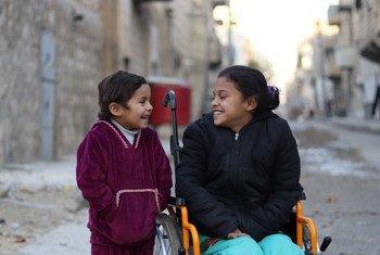 Une fille de 8 ans assise dans un fauteuil roulant à côté de sa sœur de 5 ans, près de leur maison à Alep Est, en Syrie. L’enfant paralysée a perdu l'usage de ses jambes après l’explosion d’une bombe. 11 décembre 2017.