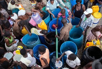 La gente afectada por el huracán Matthew, en Haití, traslada agua limpia en cubos para poder llevarla a casa.