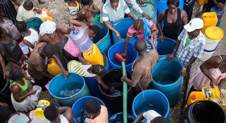 La gente afectada por el huracán Matthew, en Haití, traslada agua limpia en cubos para poder llevarla a casa.