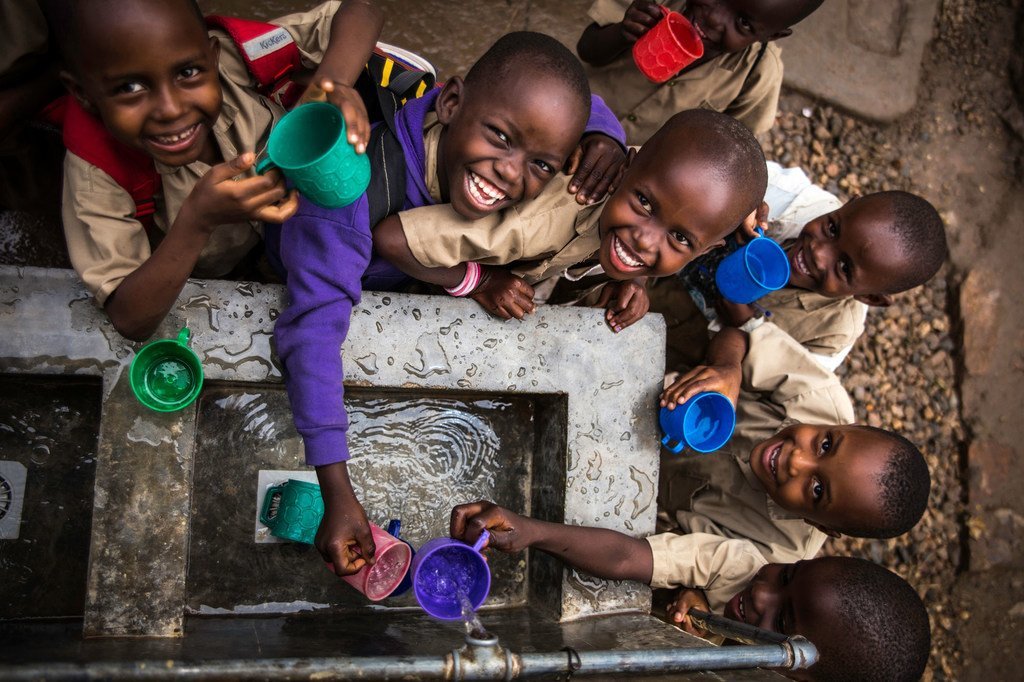Des enfants remplissent leur gobelet à un point d'eau construit par l'UNICEF dans une école primaire à Bujumbura, au Burundi.