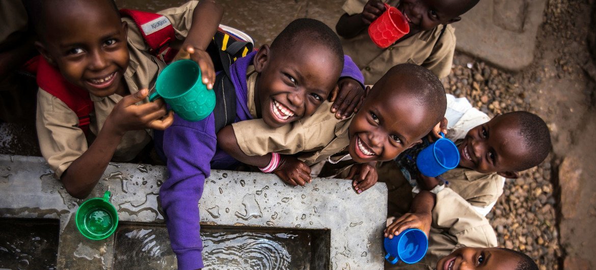 Des enfants remplissent leur gobelet à un point d'eau construit par l'UNICEF dans une école primaire à Bujumbura, au Burundi.