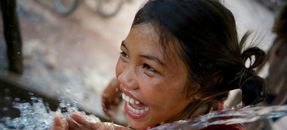Una niña sonríe mientras bebe agua de una fuente de la aldea de Adone, en República Democrática Popular Lao.