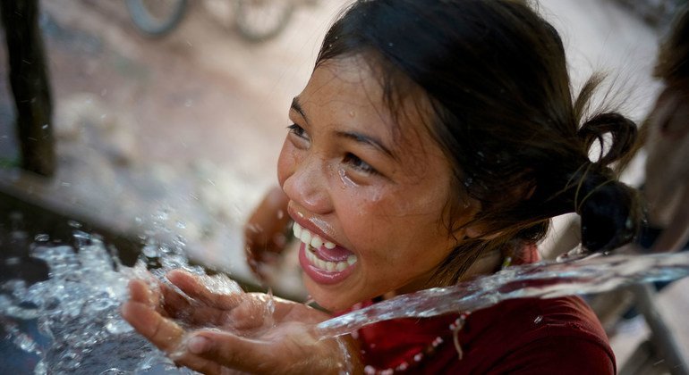 Una niña sonríe mientras bebe agua de una fuente de la aldea de Adone, en República Democrática Popular Lao.