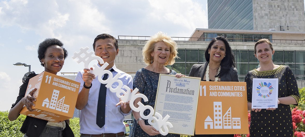 وكيلة الأمين العام لشؤون الإعلام أليسون سميل (وسط) تحمل إعلانا من مكتب عمدة نيويورك يخصص يوم الـ 11 من يوليو "يوم الأهداف العالمية للأمم المتحدة" في المدينة.