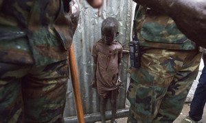 Un enfant entre des Casques bleus ghanéens dans un camp de fortune à côté d'une base de la Mission des Nations Unies au Soudan du Sud (MINUSS) à Leer.
