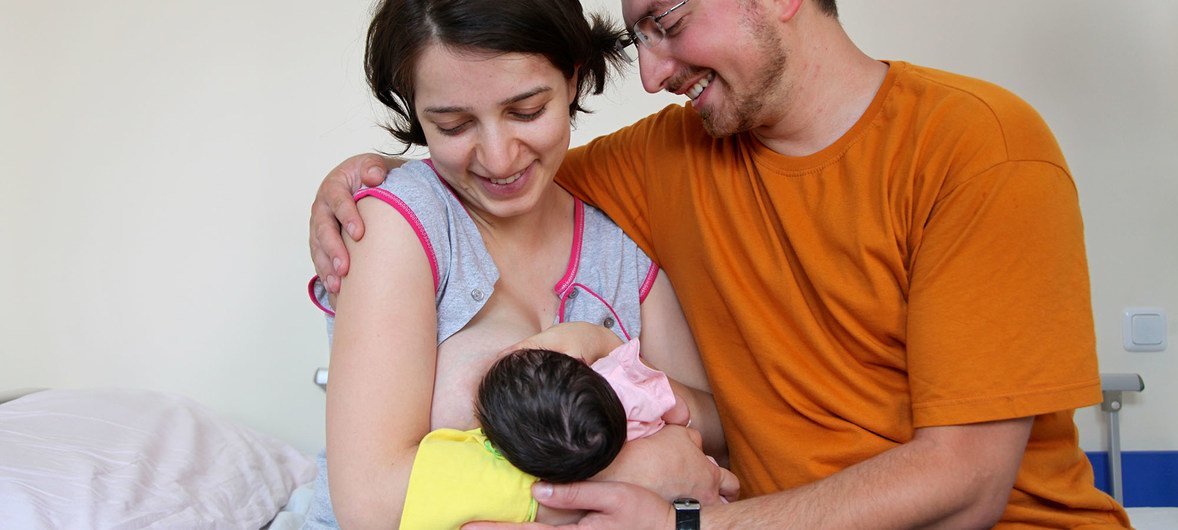  Le nouveau père est assis à côté de la femme alors qu'elle allaite leur nouveau-né à la clinique d'Erevan, en Arménie.