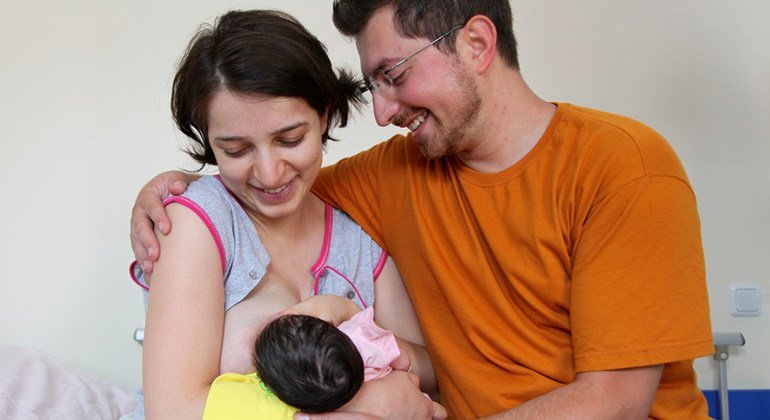  Le nouveau père est assis à côté de la femme alors qu'elle allaite leur nouveau-né à la clinique d'Erevan, en Arménie.