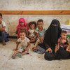 A woman and children wait as UNICEF-supported emergency humanitarian supplies are distributed in Hudaydah, Yemen, in June 2018.