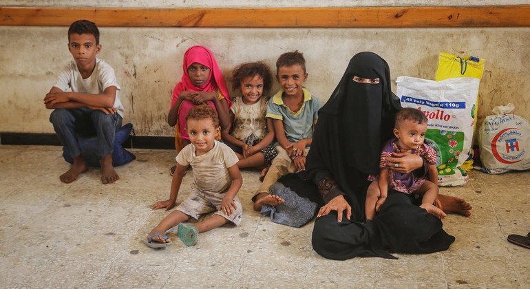 Una mujer y unos niños esperan a la distribución de ayuda de emergencia de UNICEF en Hodeida, en Yemen