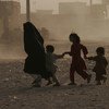 A family runs across a dusty street in Herat, Afghanistan
