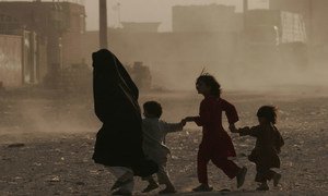 A family runs across a dusty street in Herat, Afghanistan