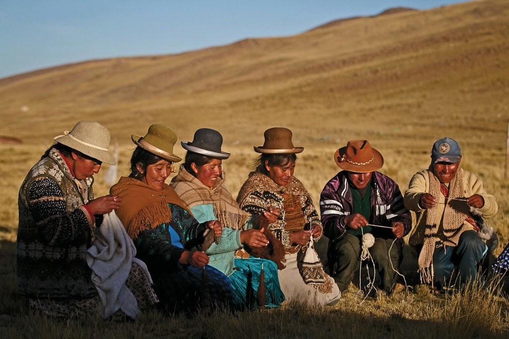 Wanaume na wanawake wa kiasili wa Nuñoa huko Puno, Peru, wakisuka mavazi kulingana na nyuzi za alpacas..