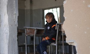 A child sitting at a desk in a school that was attacked, in Idlib, Syria. 2016.