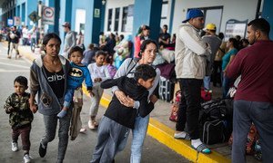 Una madre venezolana hace fila con su familia para entrar a Perú desde Ecuador. 