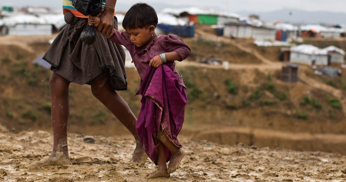 Two-year-old Rumana is led by a community worker as she and her family are relocated to a safer area of the Kutupalong-Balukhali camp, part of the refugee camp sheltering over 800,000 Rohingya refugees, Cox's Bazar, Bangladesh.
