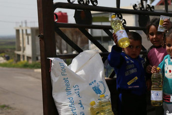 أطفال سوريون عائدون إلى بيوتهم بعد حصولهم على حصص غذاتية ومواد منقذة للحياة خلال توزيع الطعام.