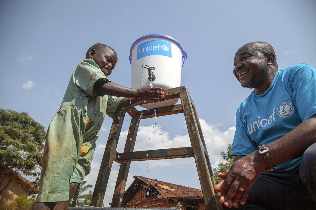 Un employé de l'UNICEF parle à une petite fille qui se lave les mains pour prévenir la propagation du virus Ebola au Nord-Kivu, en République démocratique du Congo (RDC).