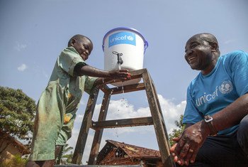 Un employé de l'UNICEF parle à une petite fille qui se lave les mains pour prévenir la propagation du virus Ebola au Nord-Kivu, en République démocratique du Congo (RDC).