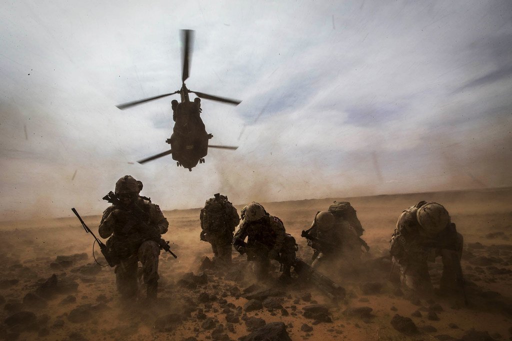 Un hélicoptère canadien CH-147 Chinook décolle alors que les Casques bleus canadiens de la MINUSMA se protègent de la poussière lors d'un exercice d'évacuation médicale près de Gao au Mali.