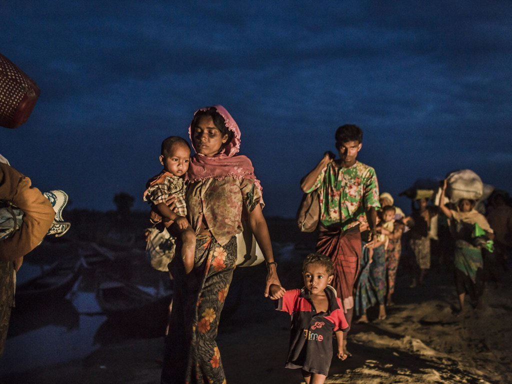 Wakimbizi wa Rohingya wanatembea kuelekea kambini huko Teknaf, Bangladesh, baada ya kuvuka Mto Naf kwa kutumia rafu za muda jioni.
