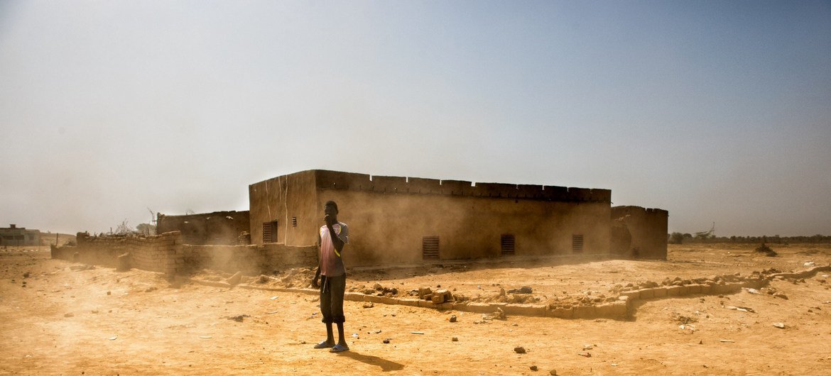 Un jeune garçon se tient sur la route alors que les vents et le sable s'accumulent dans la banlieue de Kaédi, en Mauritanie. 