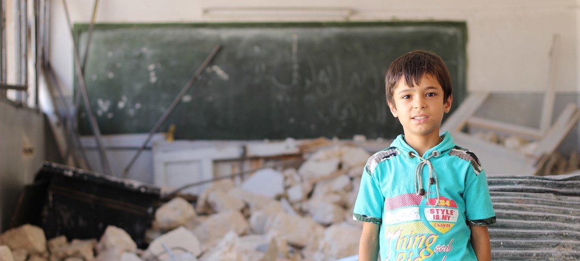 叙利亚一名境内流离失所儿童站在一所被会毁坏的教室前。