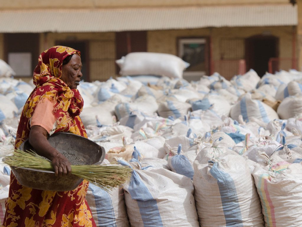 Une Soudanaise en tenue traditionnelle transporte un panier au marché aux récoltes d'Al Obaied, dans le Kordofan du Nord, entourée de grands sacs de gomme arabique récoltée.