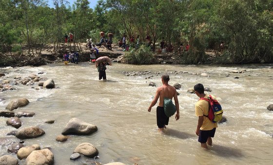 Migrantes Venezuelanos cruzando o rio Trocha, na fronteira da Colombia com a Venezuela.  