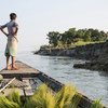 2016年10月，孟加拉国中部锡拉杰甘杰（Sirajganj）县，一个男孩站在船上眺望河岸。由于气候变化，锡拉杰甘杰的农田受到严重侵蚀，许多家庭失去生计，被迫流离失所。