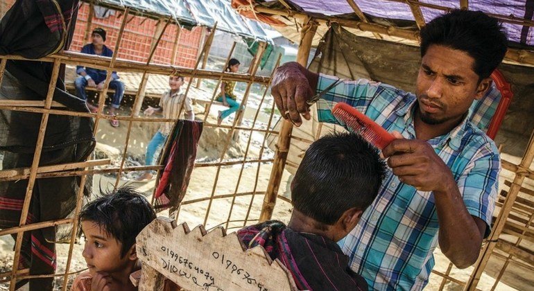 Hairdresser Najibullah, 28, cuts a customer's hair at his barber's shop in Moynerghona refugee camp, Bangladesh. Moynerghona, Bangladesh. December 2017