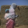 Una mujer y su hijo, desplazados por la violencia en la ciudad maliense de Tombuctú y sus alrededores, caminan por una aldea de desplazados internos en Mopti, donde viven unas 40 familias.