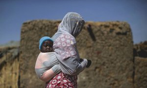 Une femme et son enfant, déplacés par la violence à Tombouctou et dans les environs, traversent un village de personnes déplacées à Mopti, où vivent une quarantaine de familles.