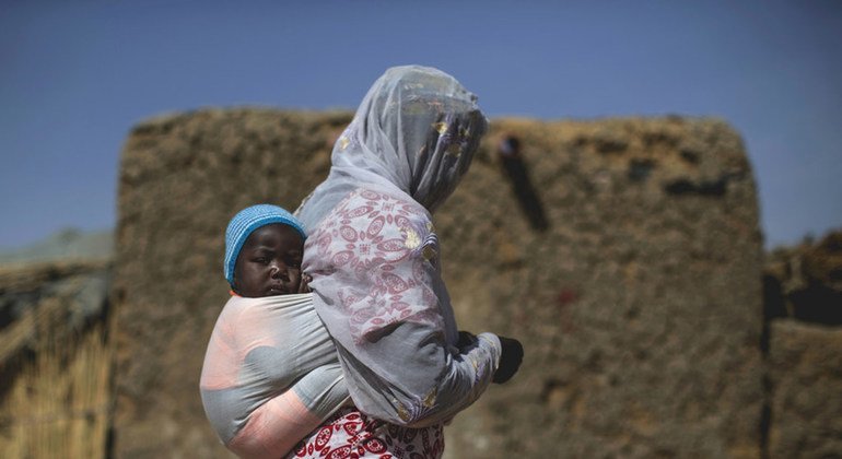 Une femme et son enfant, déplacés par la violence à Tombouctou et dans les environs, traversent un village de personnes déplacées à Mopti, où vivent une quarantaine de familles.