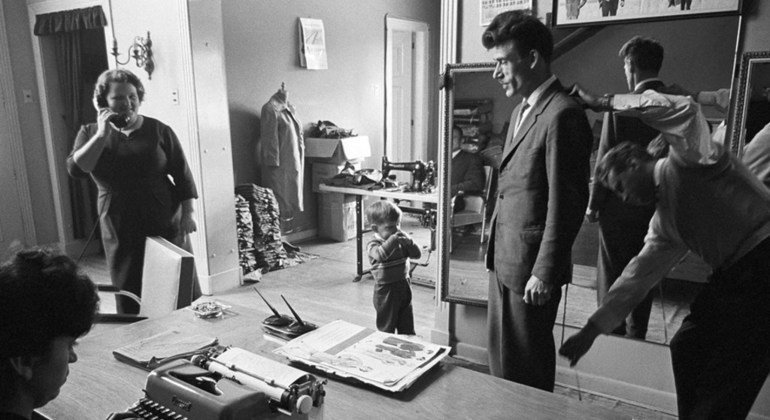 1961年，为纪念世界难民年，有150个难民家庭被哥伦比亚接收。这家裁缝店的主人之一（左二手持电话者），以及正在店内测量尺寸的男士都是当时刚刚进入该国的难民。