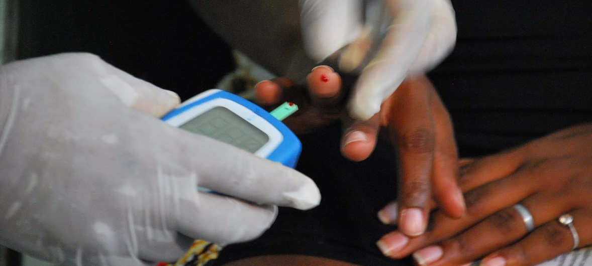 A health worker checks a patients blood sugar levels with blood glucose meter.